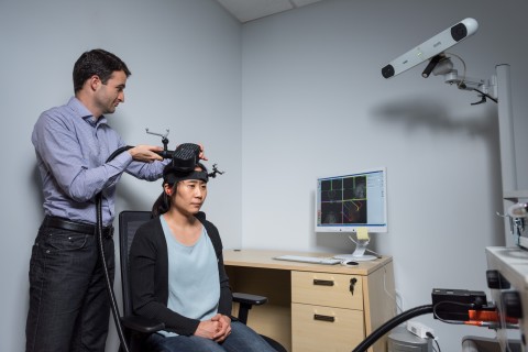 A researcher uses a non-invasive neural stimulation tool.